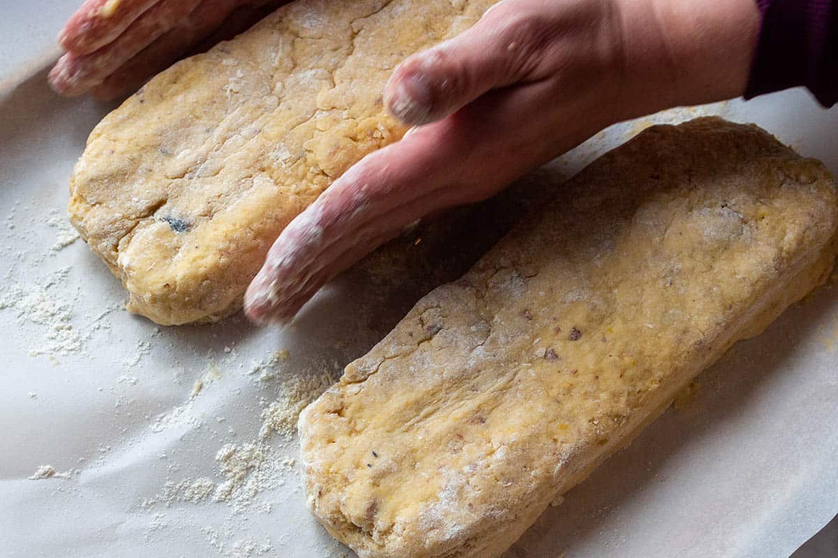 Two hands forming dough into two rectangle shapes. 