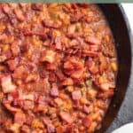 Cast iron pan full of baked beans and bacon.