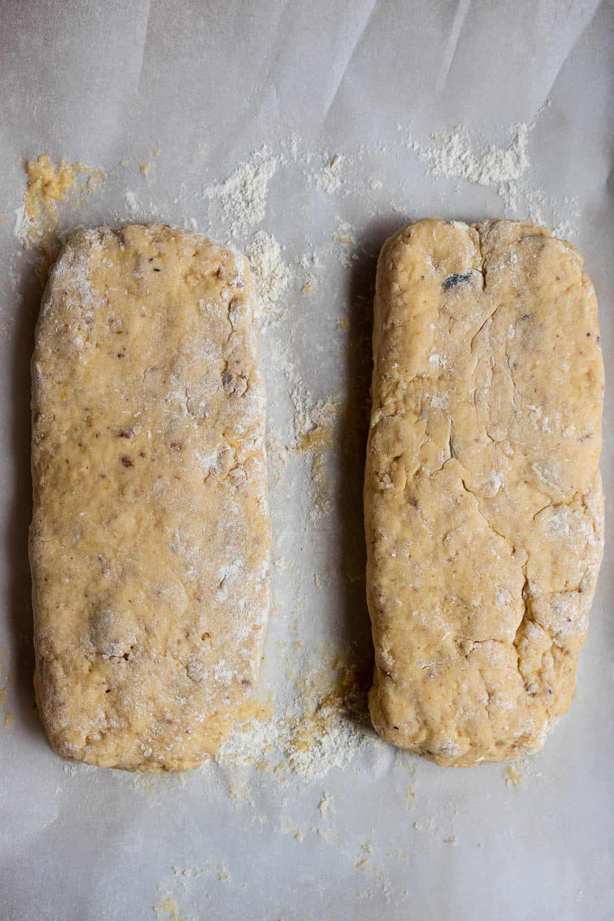 Two balls of dough formed into rectangle shapes sitting on parchment paper. 