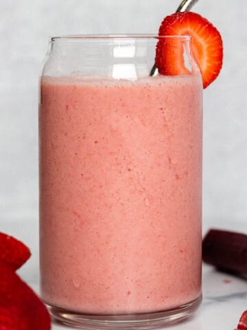A glass with a fresh slice of strawberry.