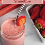 A glass with a smoothie and slice of fresh strawberry and fresh rhubarb and strawberries.