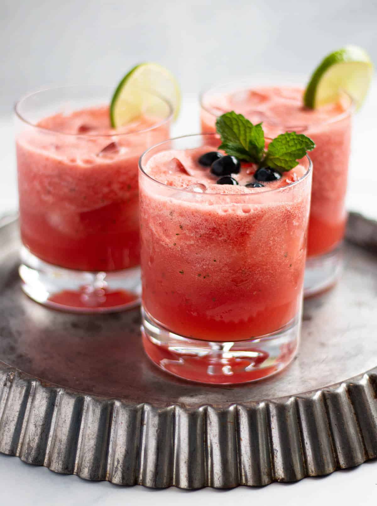 Tart pan with three old fashioned glasses filled with watermelon limeade, fresh mint and lime slices. 