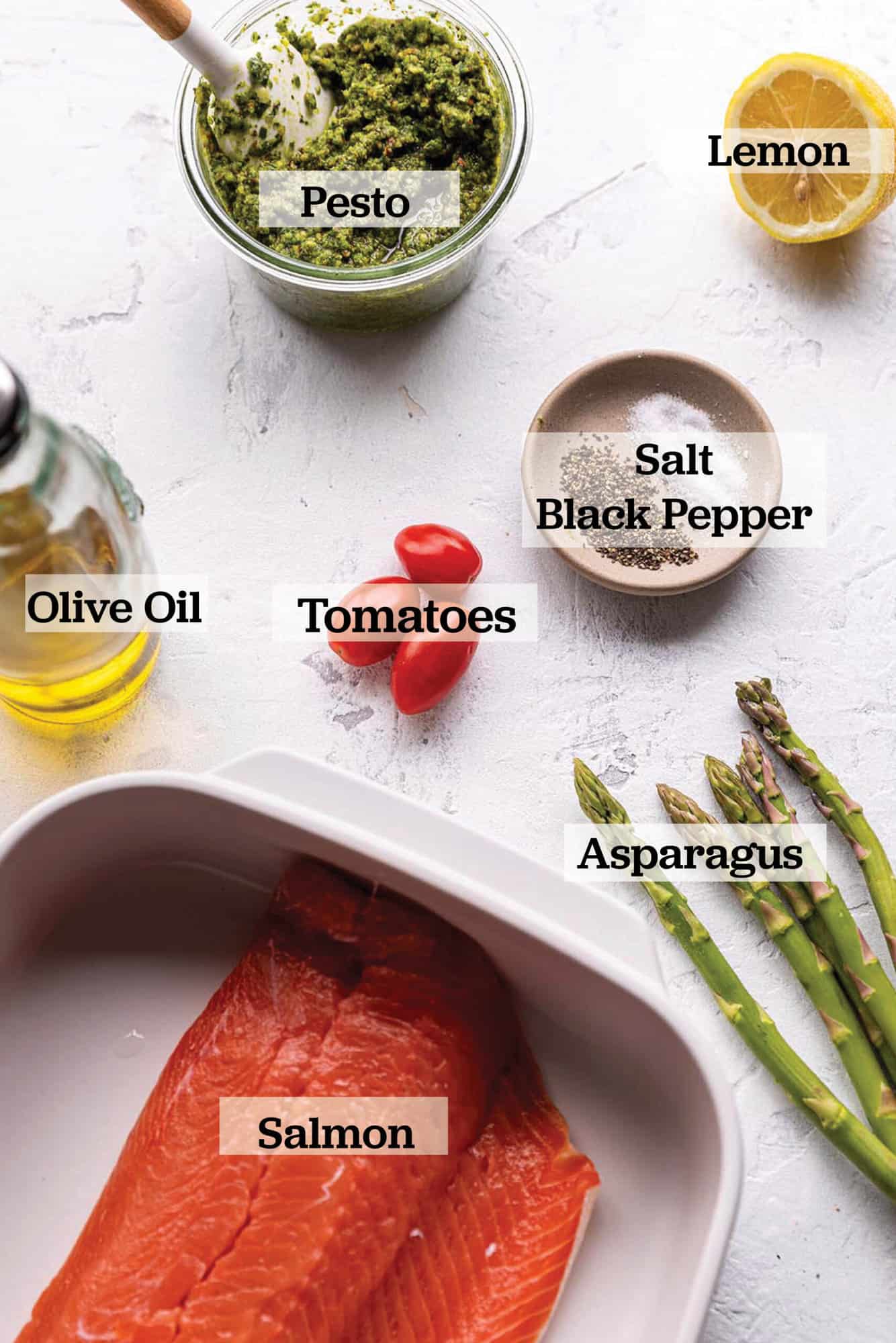 A salmon filet with asparagus, pesto, a lemon, cherry tomato, olive oil, salt and pepper.
