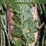Baking sheet with green beans, and salmon topped with pesto.