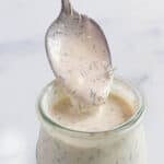 A small weck jar with a creamy sauce with a spoon scooping some out.