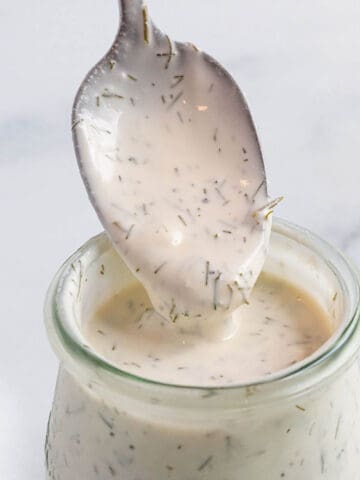 A small weck jar with a creamy sauce with a spoon scooping some out.