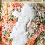 Baked salmon filet with a white sauce on top of rice.