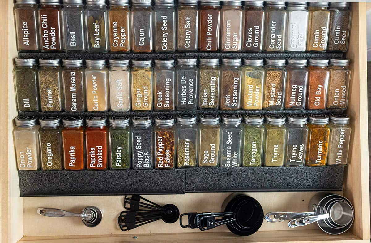 Large spice drawer with metal organizer, spices, measuring cups and measuring spoons.