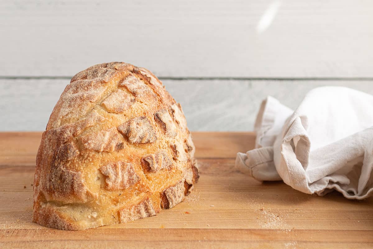 A loaf of sourdough bread cut in half face down on a cutting board. 