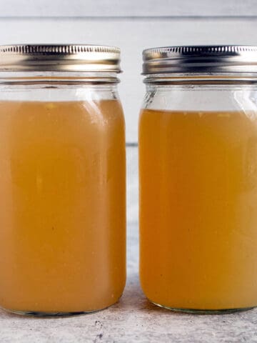 Two large mason jars with a homemade turkey broth and lids on top.