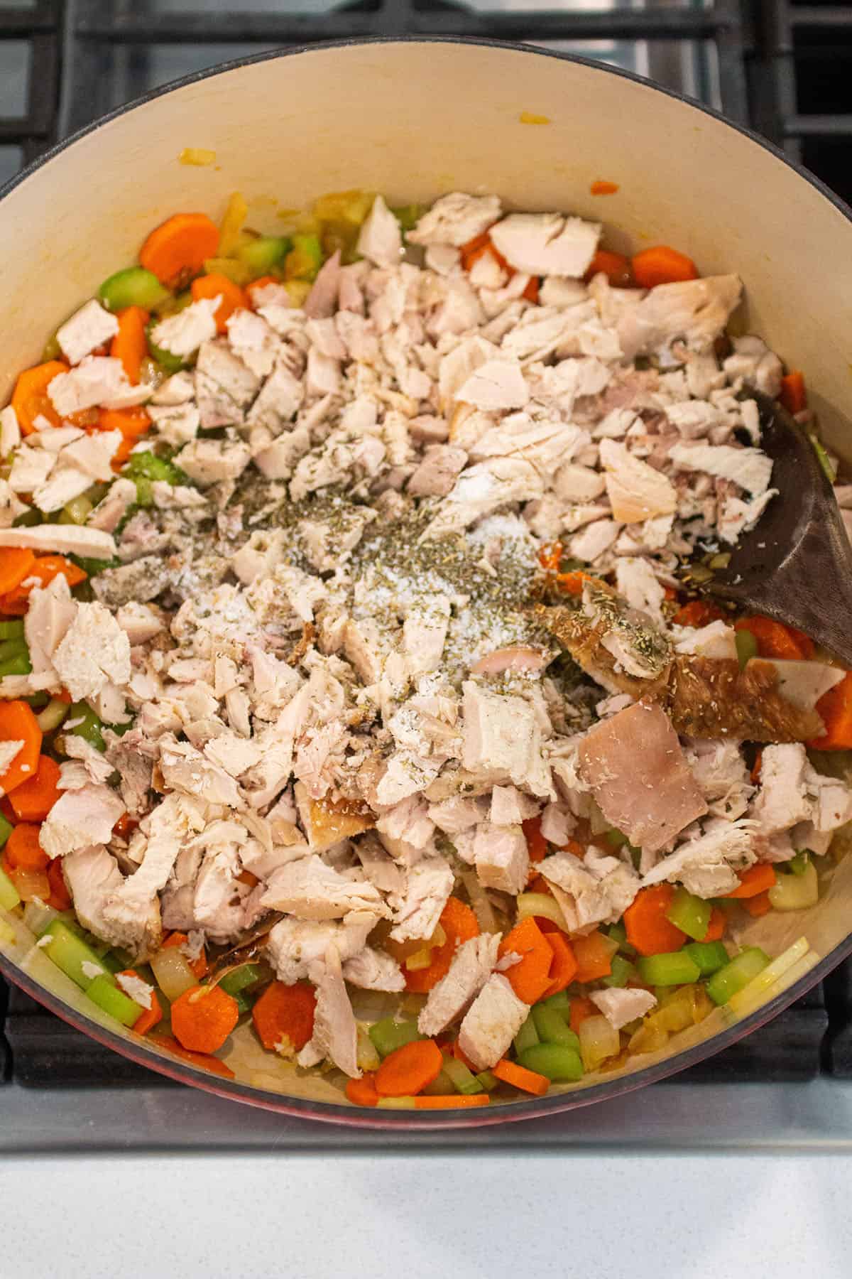 A large Dutch Oven with sautéed veggies, turkey meat and spices.