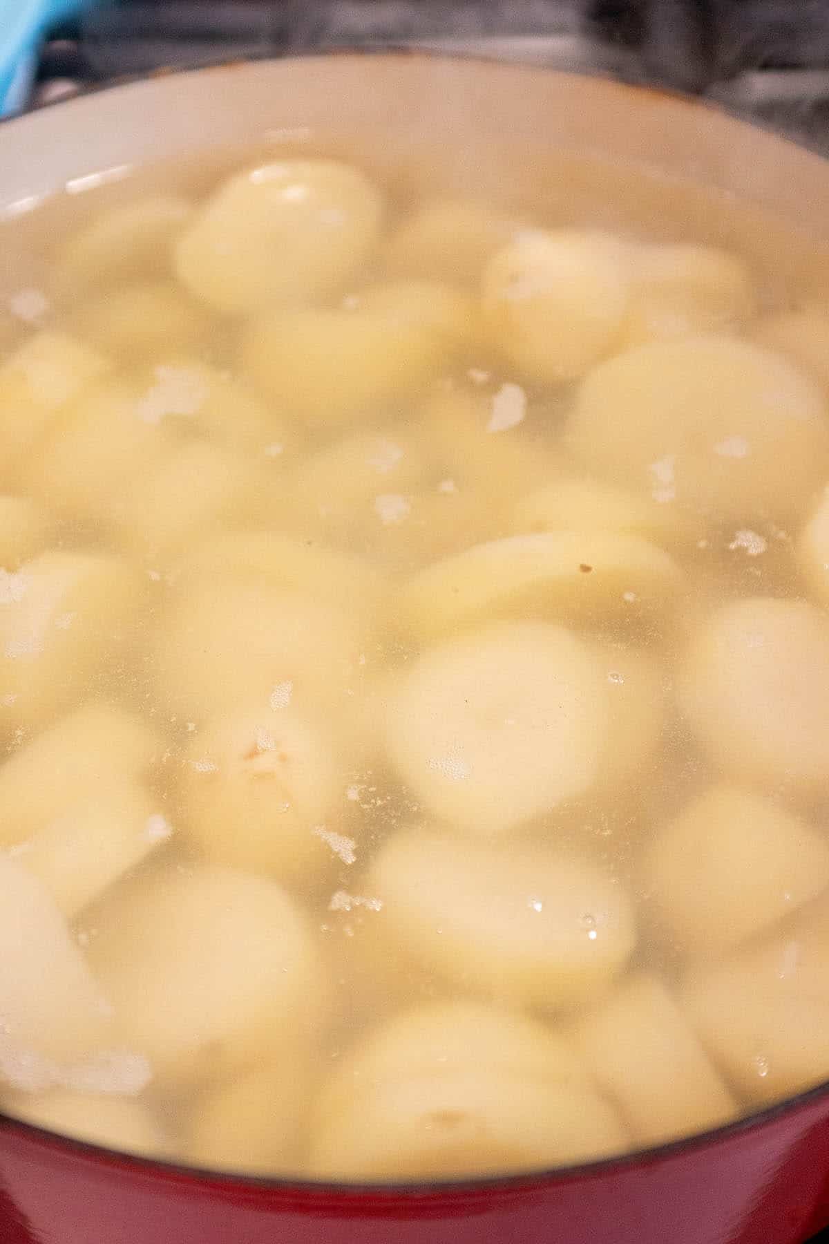A large dutch oven with diced potatoes being boiled in water.