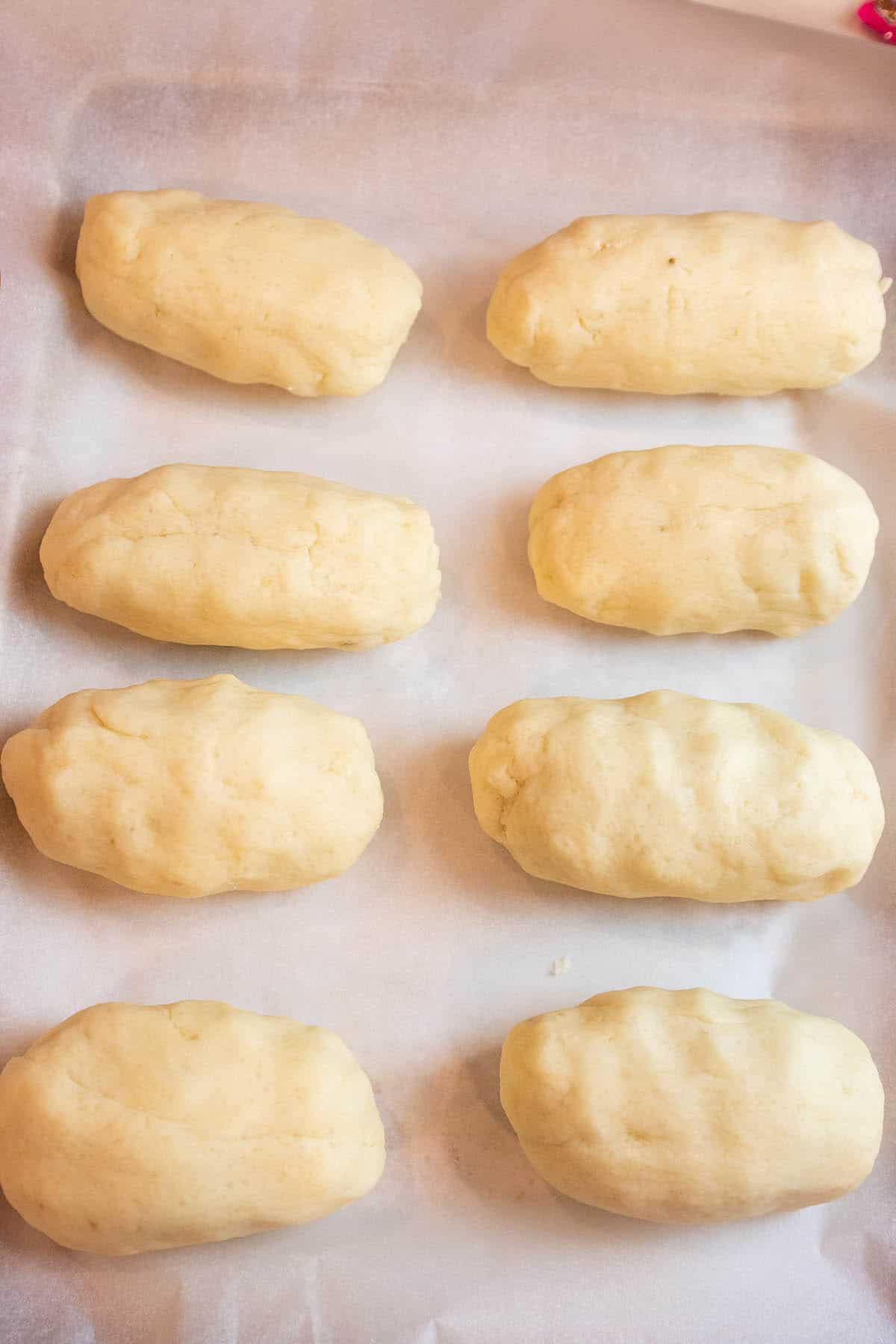 Balls of potato dough sitting on parchment paper.