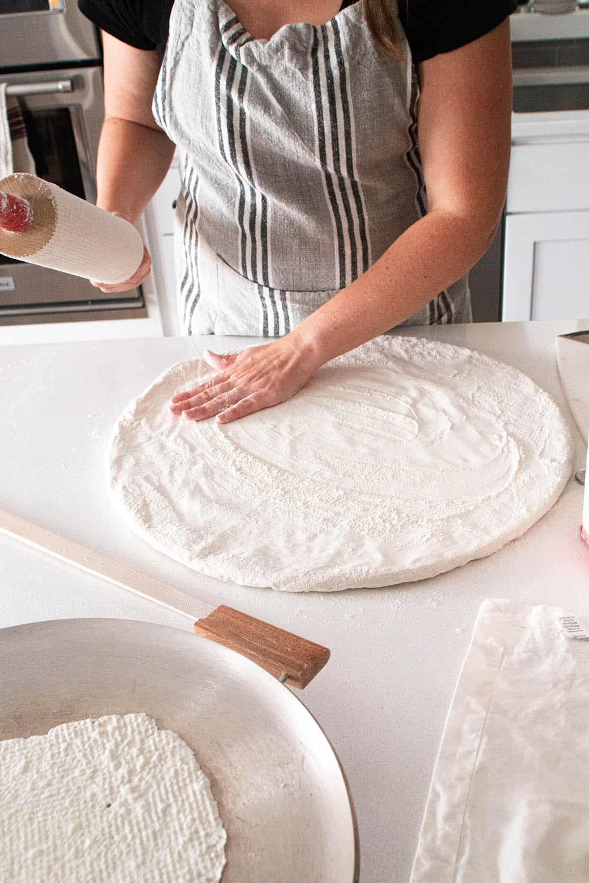 A pastry board with a baker spreading flour all over.