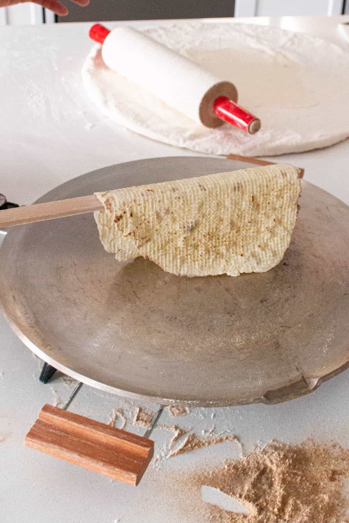 A finished piece of lefse that is golden brown and has dark brown spots.