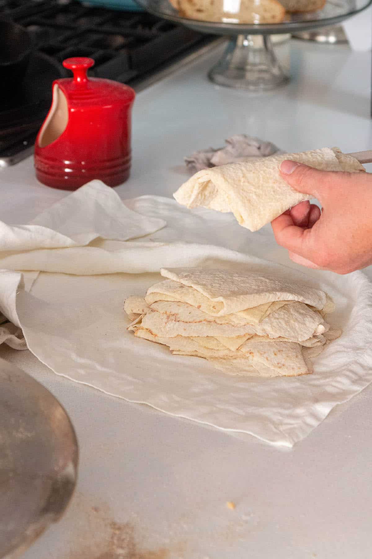 Pieces of lefse folded into triangles and stacked on one another inside a cloth towel too cool. 