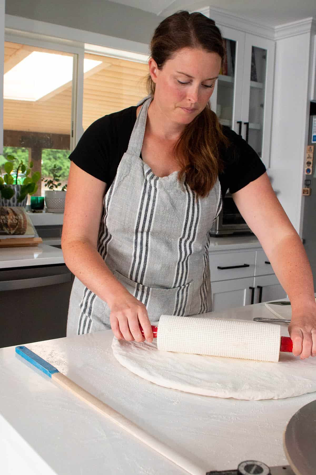A baker with a rolling pin making thin lefse. 