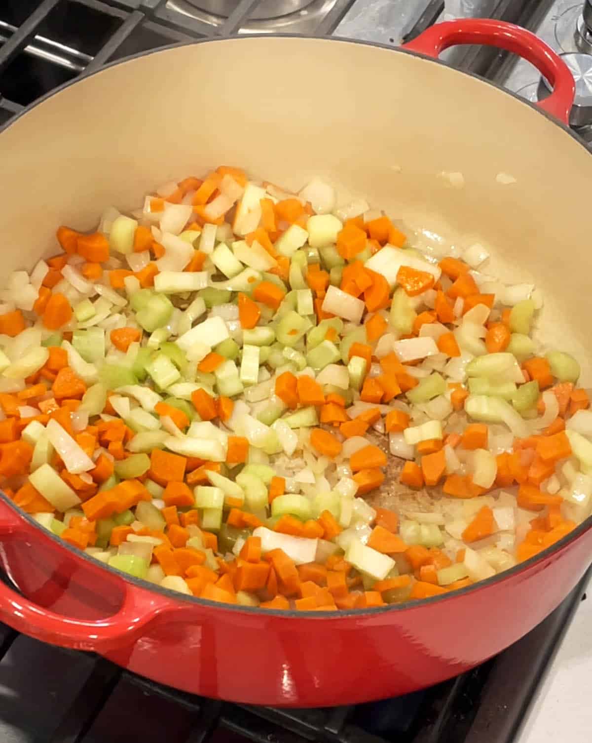 A large Dutch Oven with carrots and celery sautéing.