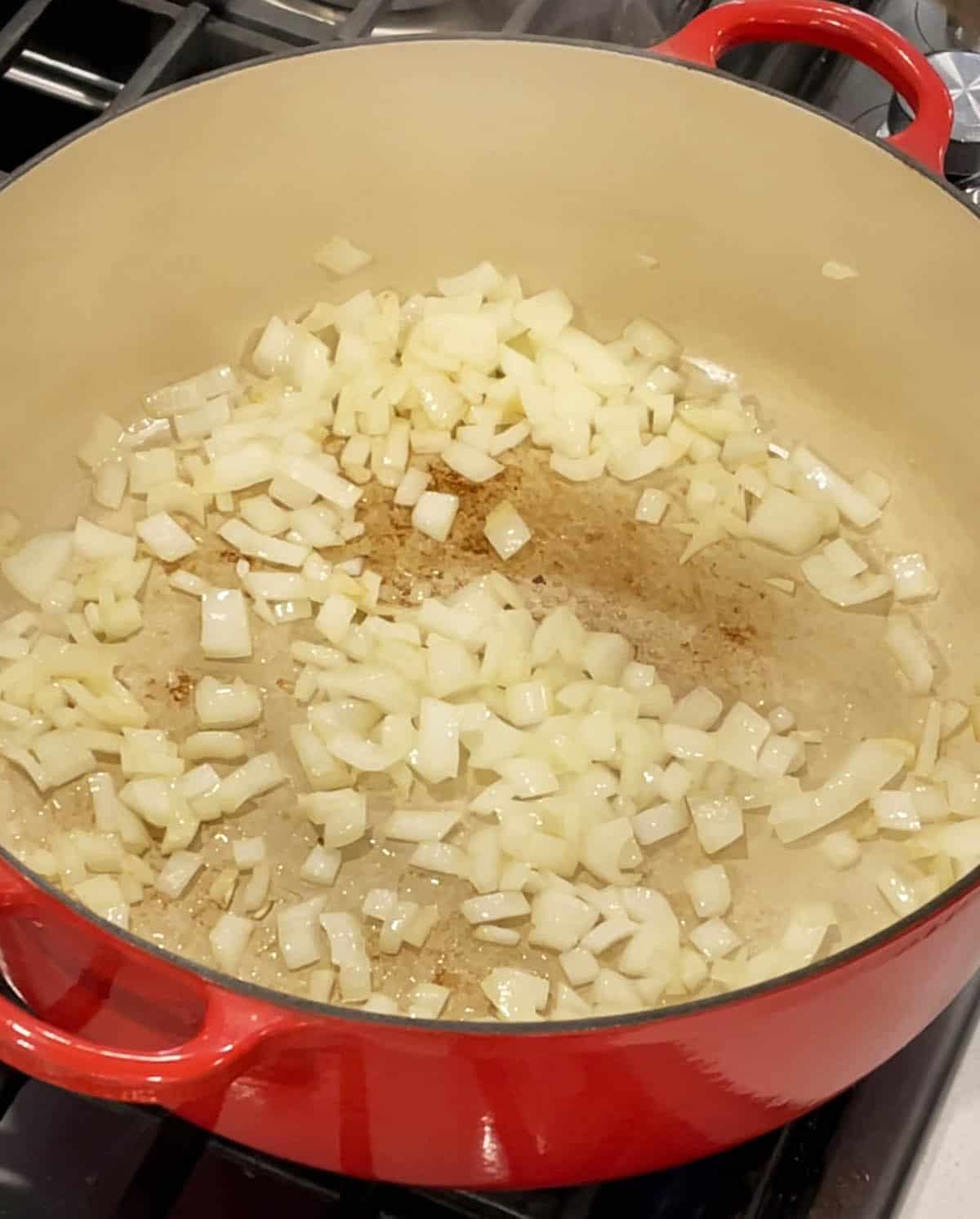 A large Dutch Oven with onions sautéing in olive oil