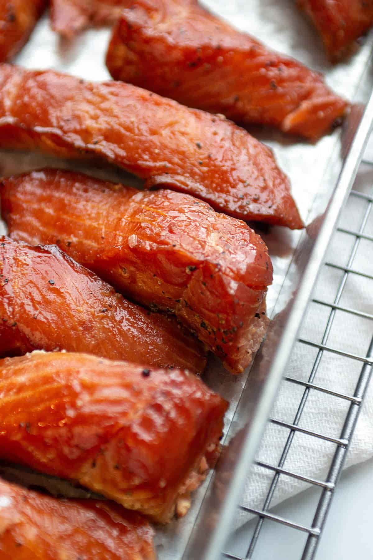 A wire rack with a metal pan filled with smoked salmon.