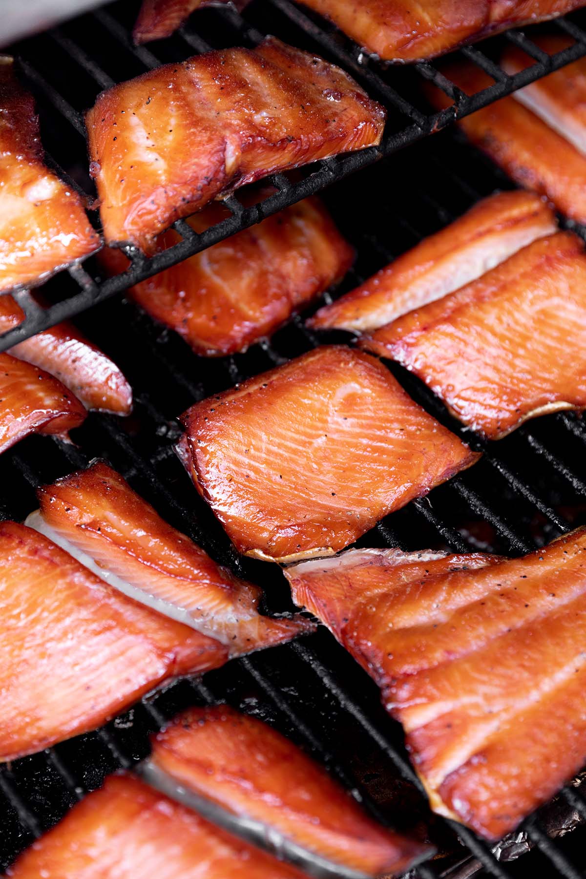 Salmon filets smoked sitting on a grill grate. 