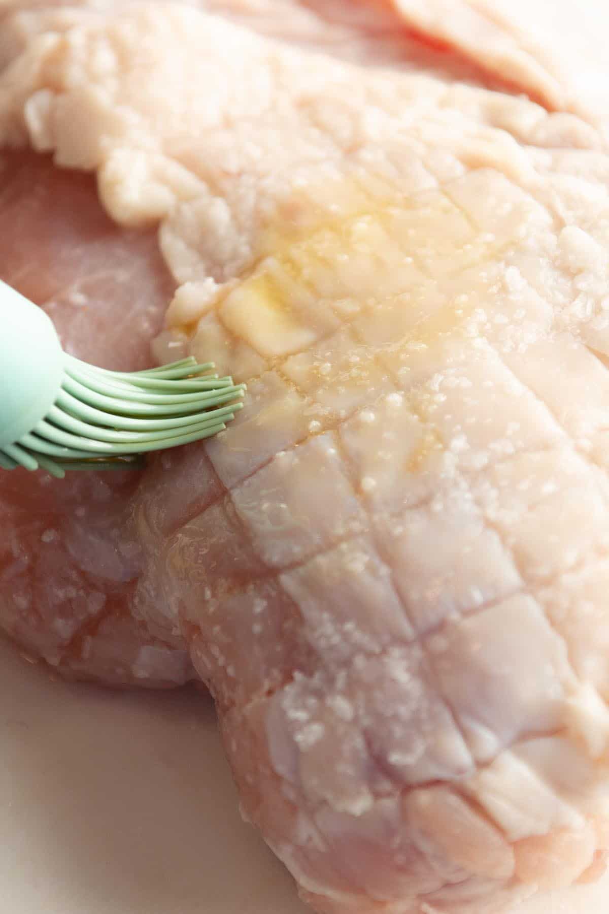A turkey breast with olive oil being spread all over. 