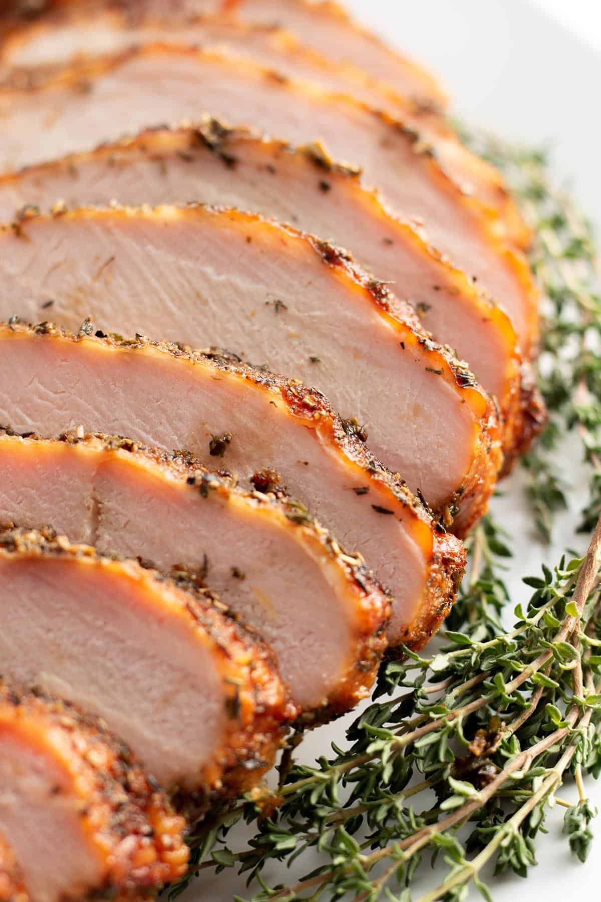 Slices of a smoked turkey breast with fresh thyme.