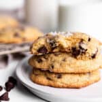 A stack of 3 sourdough chocolate chip cookies with milk in the back.