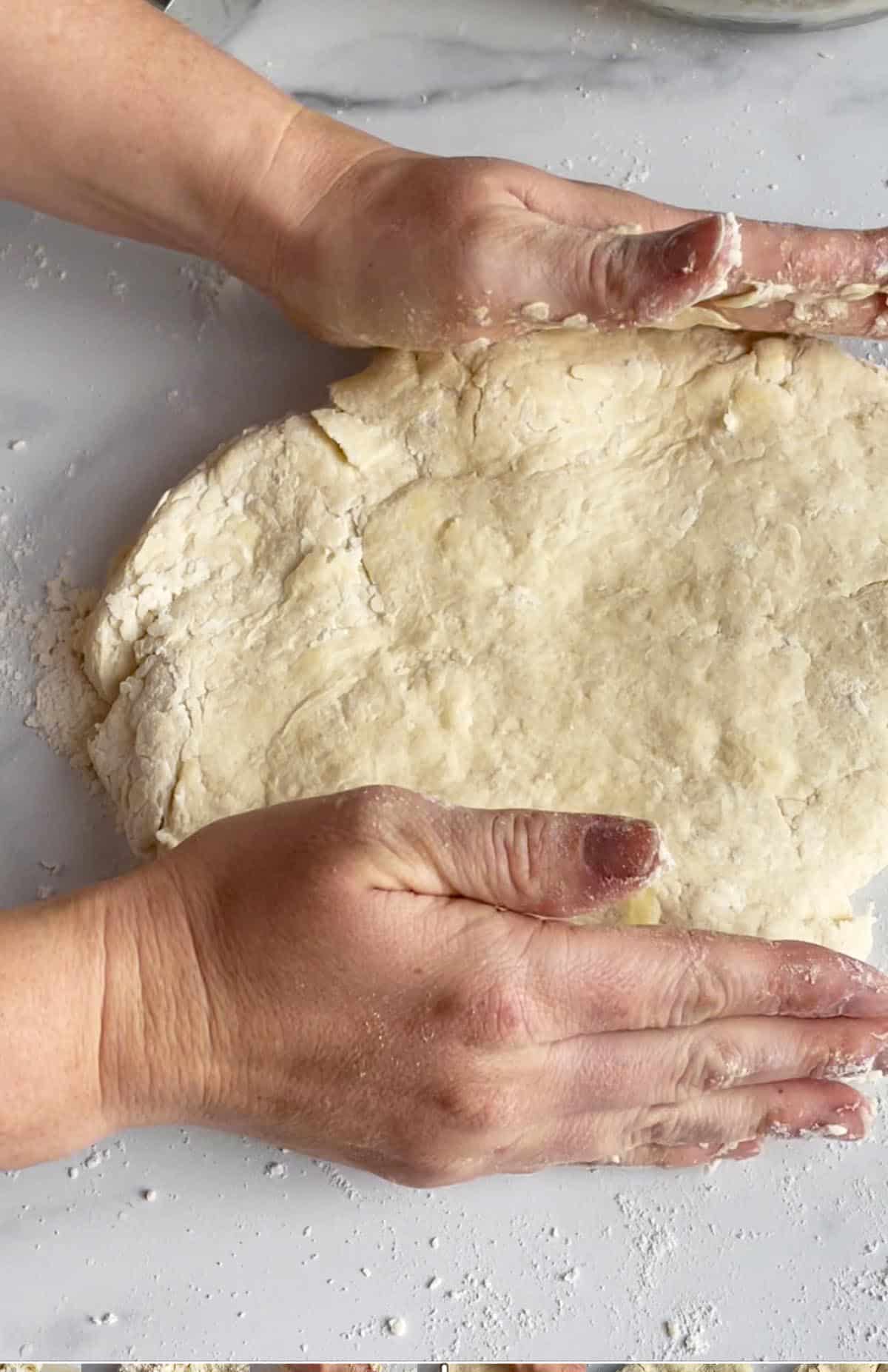 Two hands forming scone dough into a round circle.