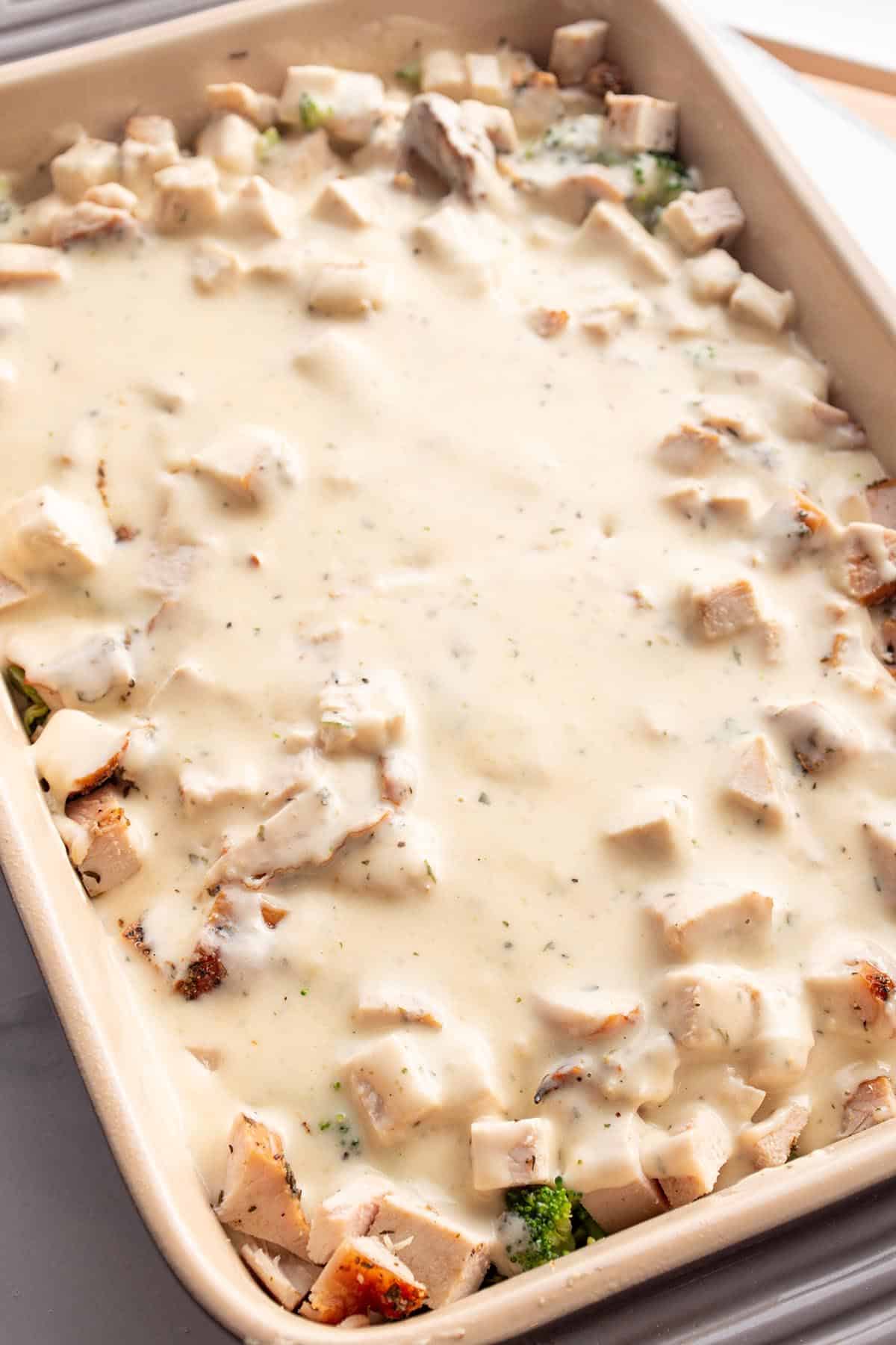 A baking dish with layers of broccoli, turkey, and a creamy sauce.