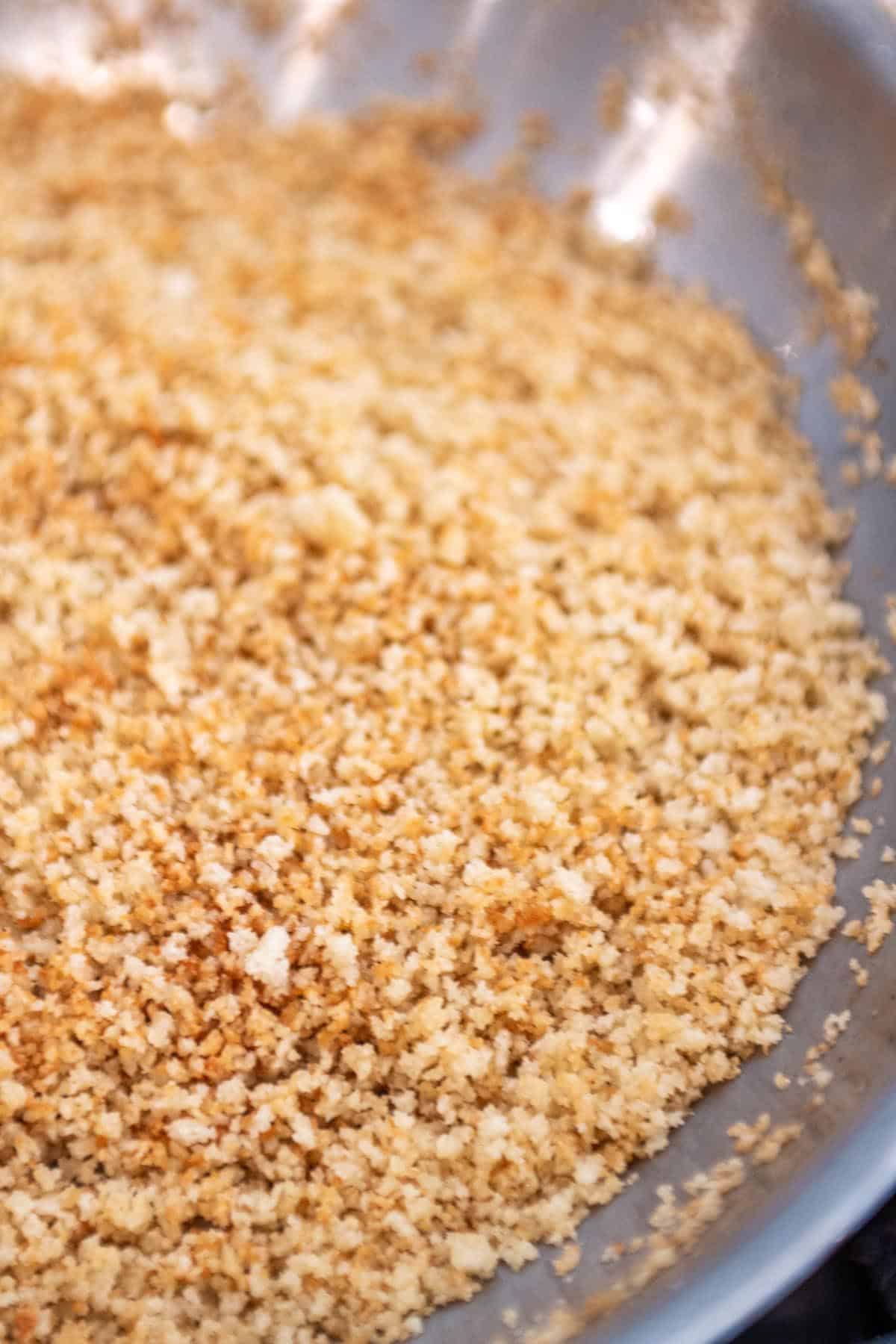 A pan with panko crumbs being toasted.