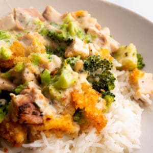 A plate with rice topped with a creamy cheese sauce, broccoli and leftover turkey.