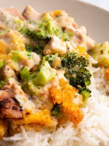 A plate with rice topped with a creamy cheese sauce, broccoli and leftover turkey.