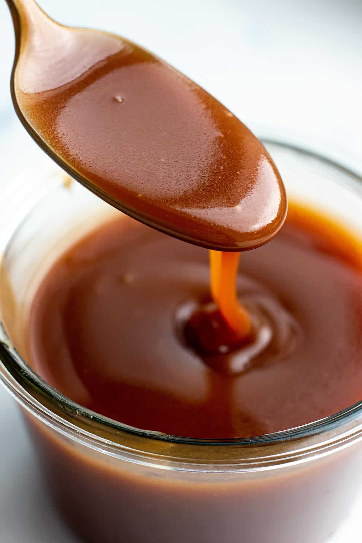 A weck jar with a caramel sauce and a spoon scooping some out.