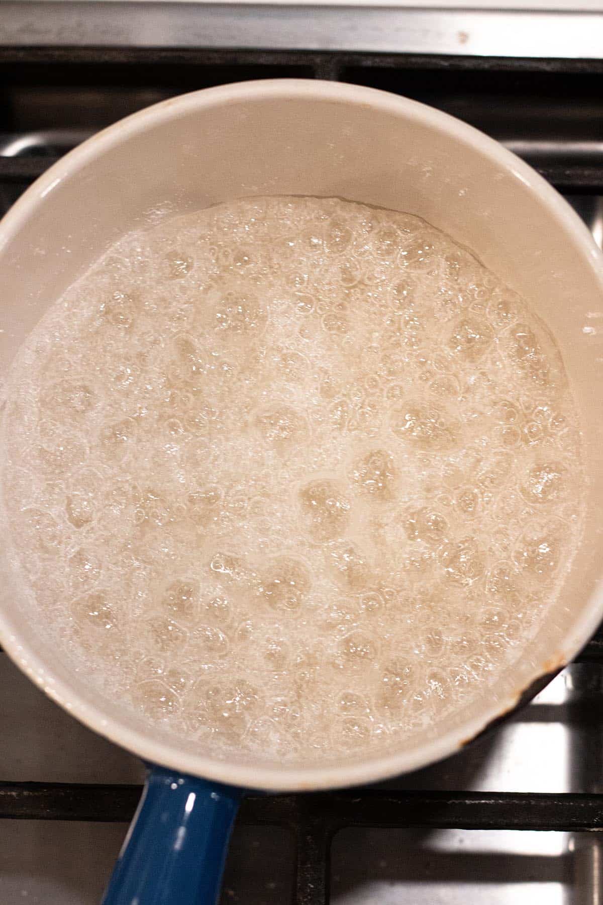 A small sauce pot with bubbling sugar and water.
