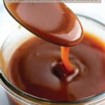 A glass jar with a creamy bourbon caramel sauce being drizzled off a spoon.