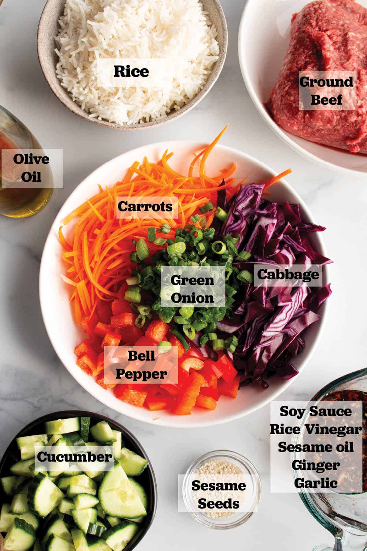 Ingredients in prep bowls. Ground beef, Cooked rice, olive oil, cucumbers, sesame seeds, a soy sauce mix, and a bowl of julienne carrots, chopped peppers, cabbage and green onions. 