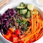 A bowl filled with fresh produce and ground beef topped with sesame seeds.