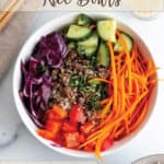 A white bowl with ground beef, shredded carrots, peppers cabbage and cucumbers.