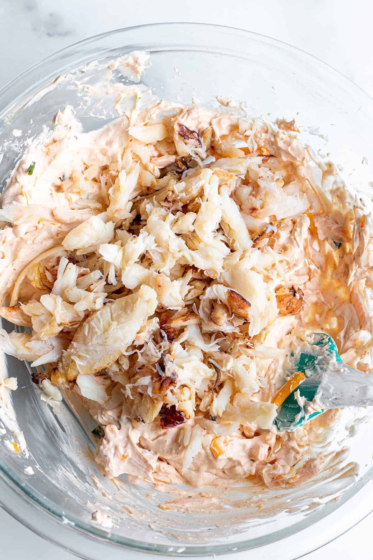 A glass bowl with a cream cheese mix topped with fresh crab meat.