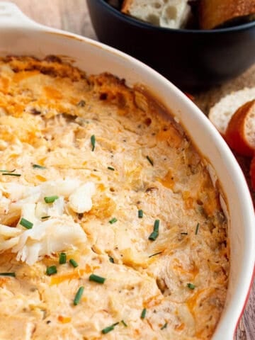 A baking dish with a cheesy crab dip with fresh crab and chives on top.