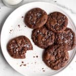 A white plate with chocolate sourdough cookies with sea salt on top.