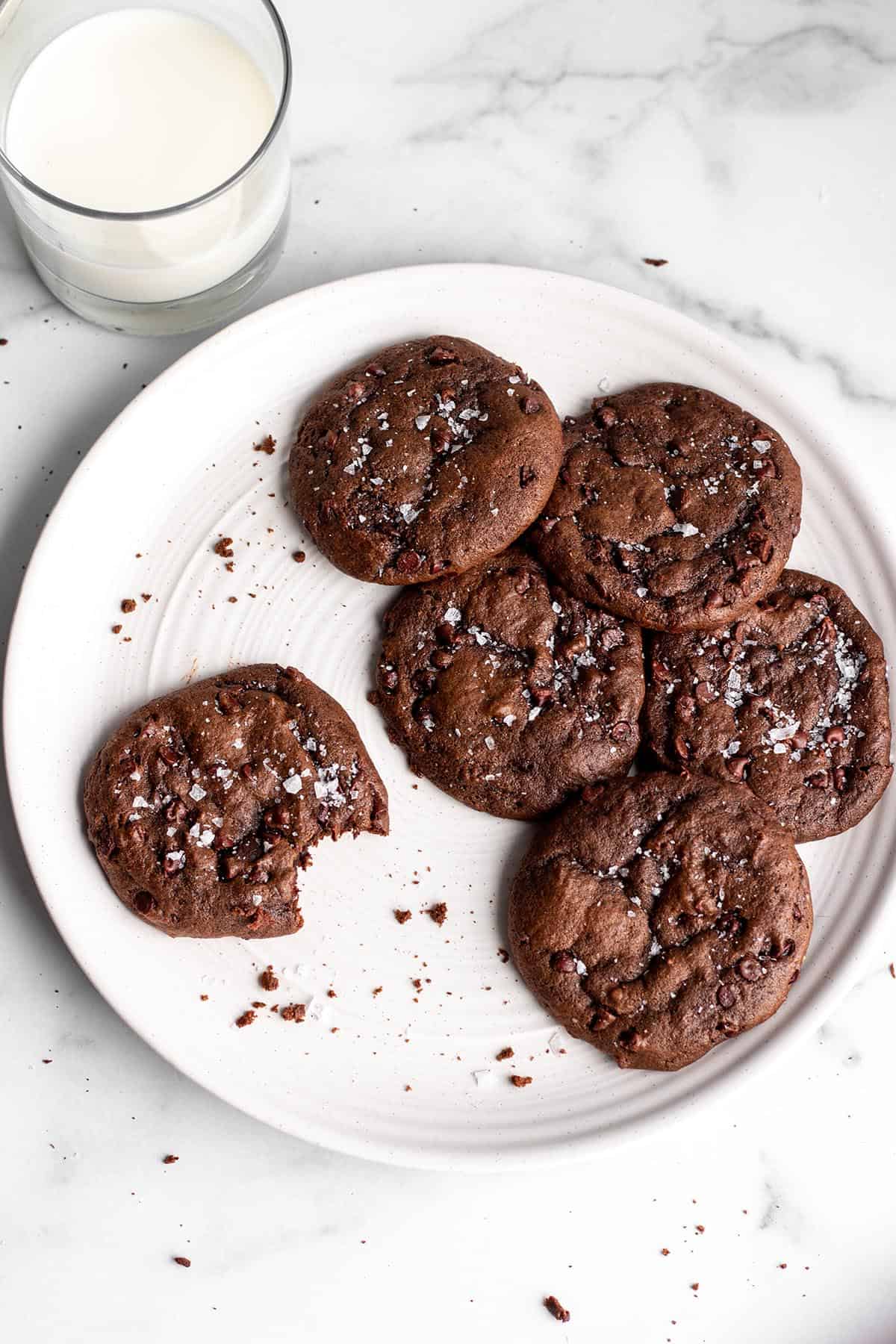 A white plate with sourdough discard chocolate cookies with sea salt on top.