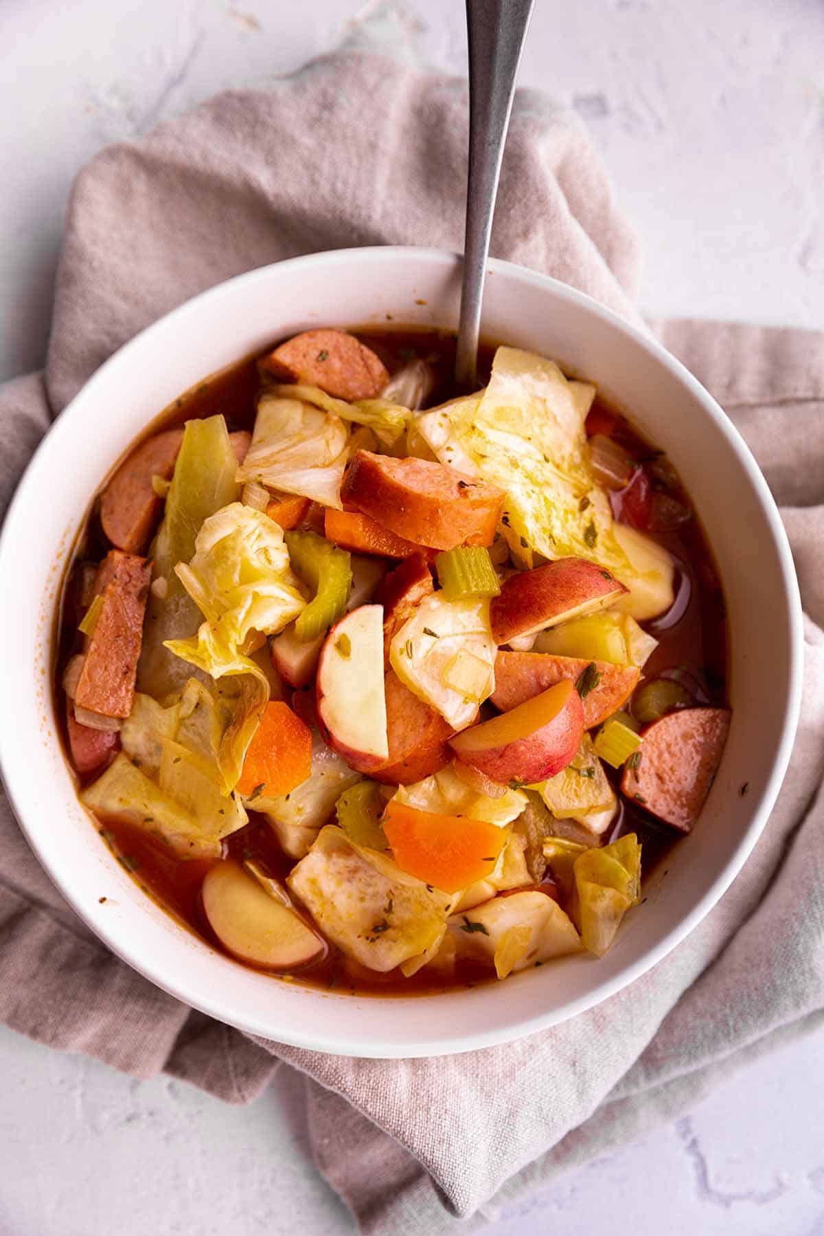 A bowl of cabbage soup with potatoes and sausage.