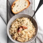 Small bowl with a crab risotto and topped with fresh crab with a slice a bread.