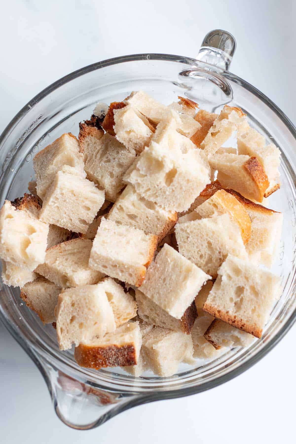 A glass measuring bowl with chunks of sourdough bread.