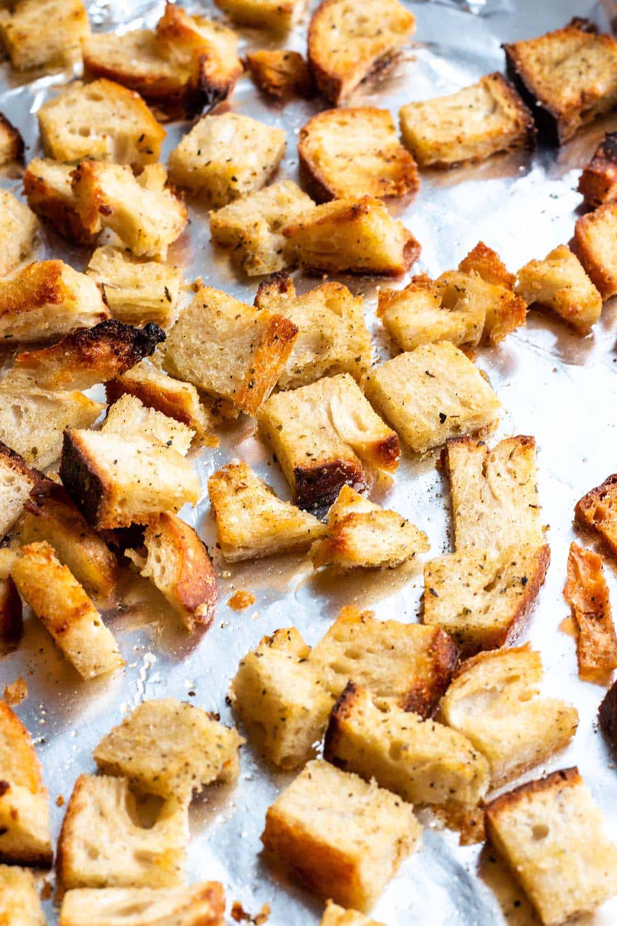 A baking sheet with tin foil and homemade croutons. 