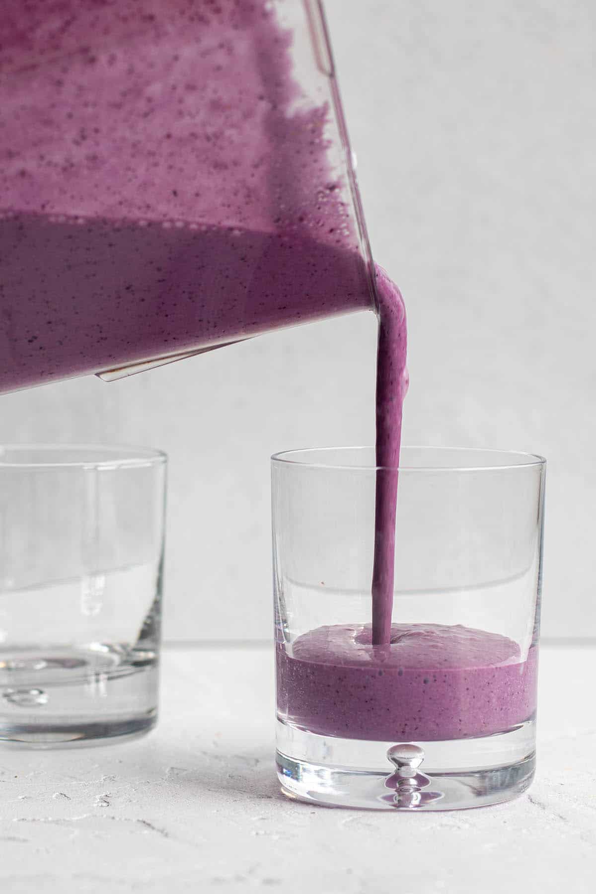 A blender pouring a smoothie into a glass.
