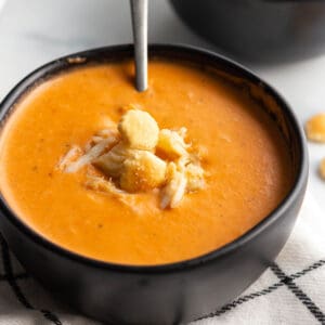 A black bowl with a creamy bisque soup with fresh crab on top.