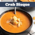 Two bowls of crab bisque topped with oyster crackers and crab.